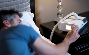 un homme allongé dans son lit utilisant un téléphone