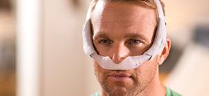 Homme portant un masque de traitement de l'apn&eacute;e du sommeil
